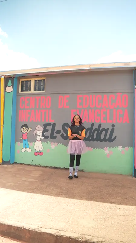 Fachada colorida de creche com voluntária à frente
