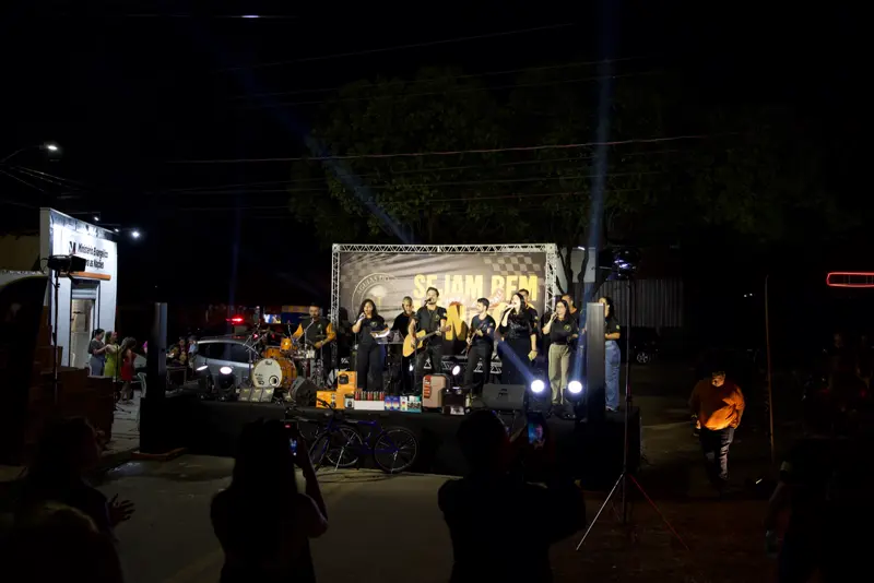 Vista noturna do evento com palco iluminado e público