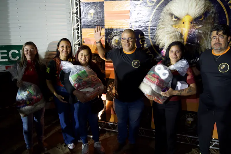 Participantes com sacolas de doação e voluntários