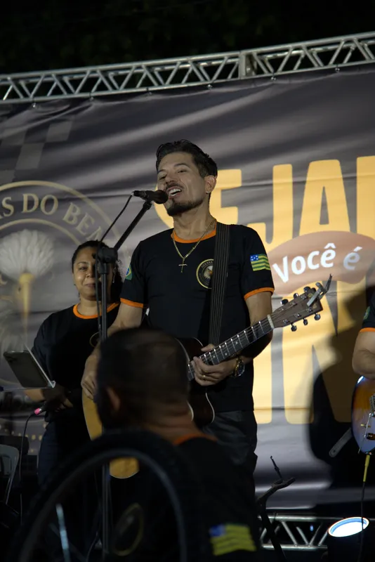 Músico cantando com violão no palco