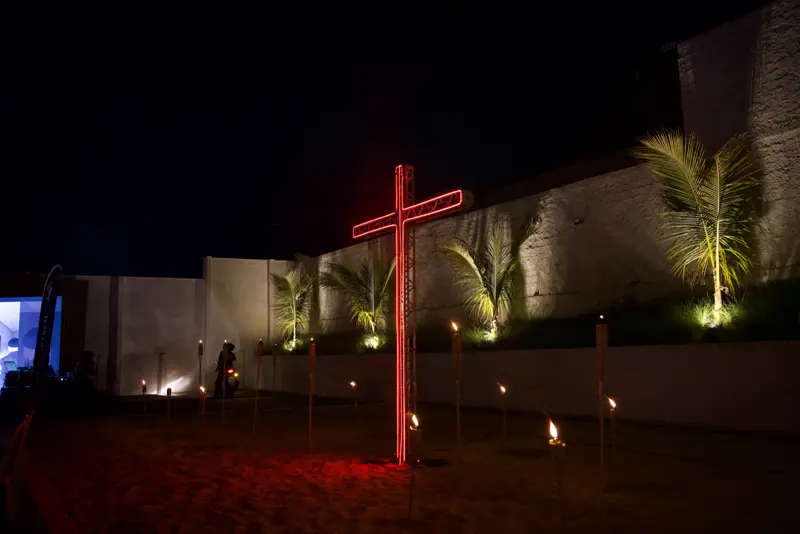 Cruz iluminada em vermelho no jardim do evento
