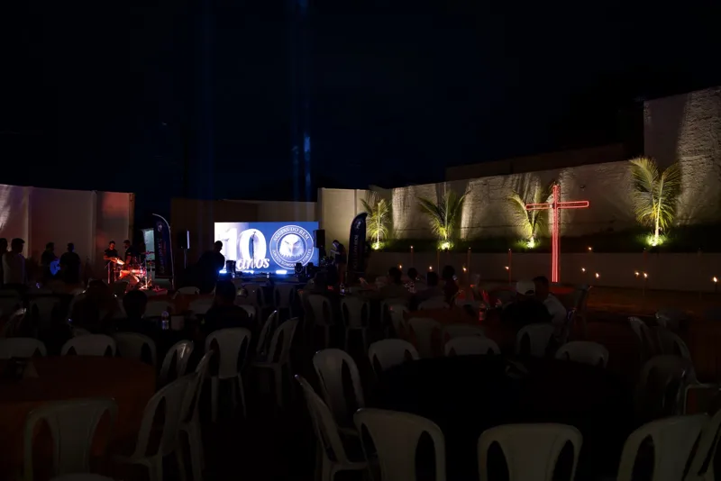 Pátio do evento com telão dos 10 anos e cruz iluminada