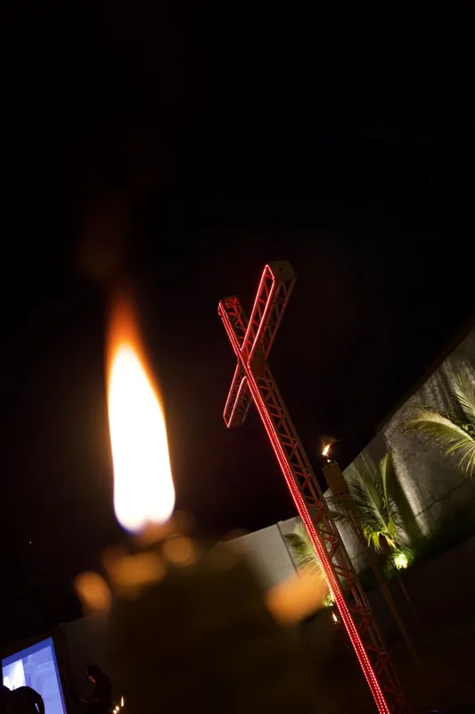 Tocha acesa e cruz vermelha iluminada à noite