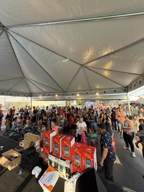 Público reunido sob a tenda com caixas de presentes à frente