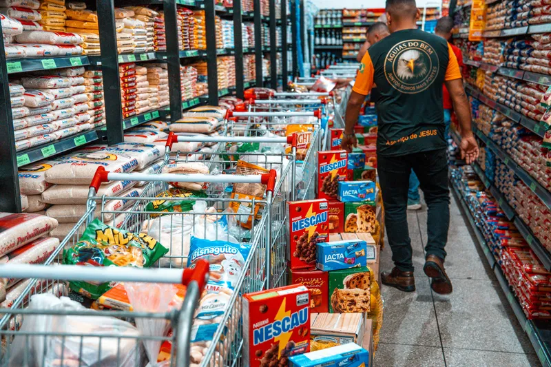Voluntário no corredor do supermercado entre carrinhos cheios de alimentos