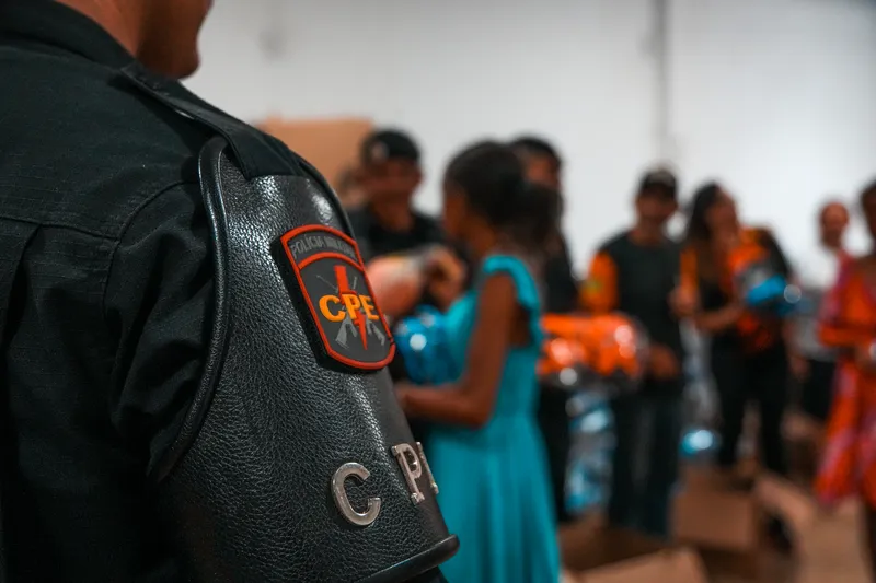 Brasão do CPE no ombro de policial durante a entrega de brinquedos