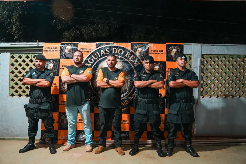 Voluntários e policiais do CPE diante do painel do grupo Águias do Bem