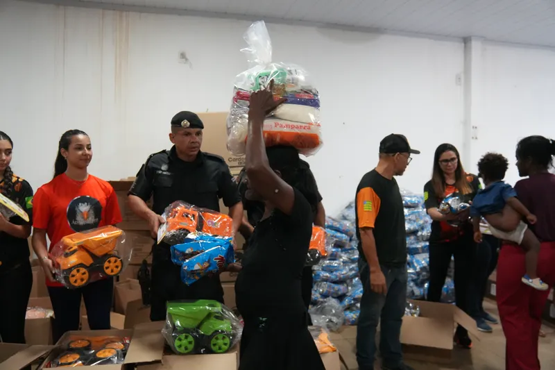 Voluntários e policiais organizando a entrega das cestas do Natal